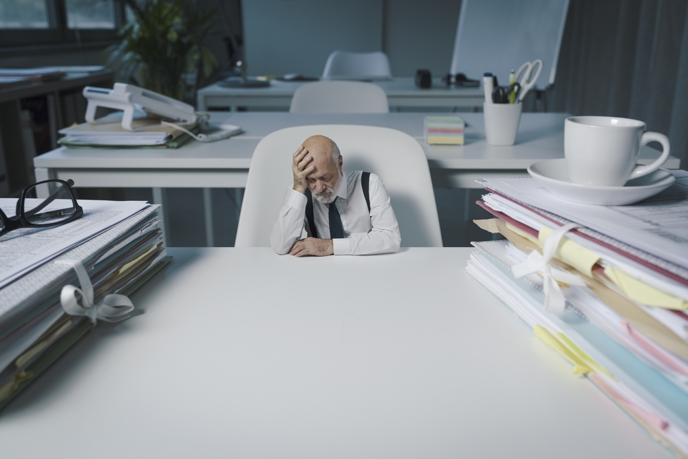 Tiny,Businessman,Sitting,At,Office,Desk,And,Thinking,,He,Is
